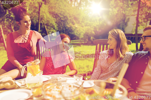 Image of happy friends having dinner at summer garden party