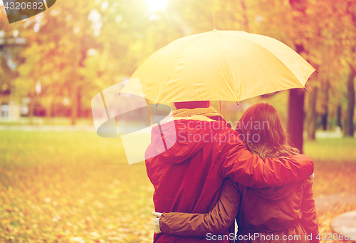 Image of happy couple with umbrella walking in autumn park