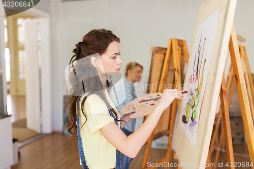 Image of student girl with easel painting at art school