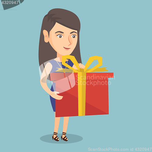 Image of Young caucasian woman holding a box with gift.