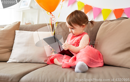 Image of baby girl with tablet pc on birthday party at home