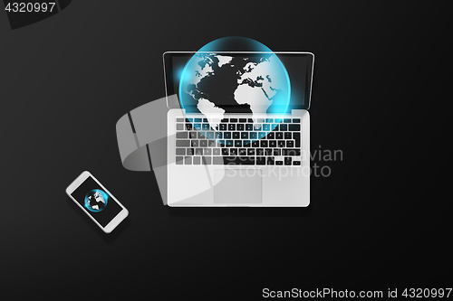 Image of laptop with earth projection and smartphone