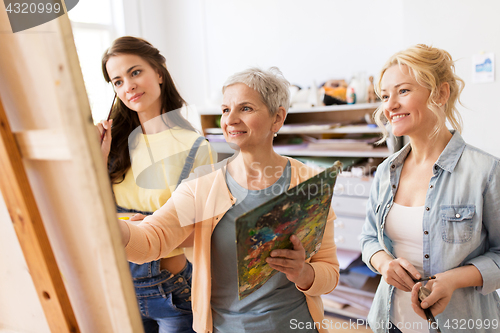 Image of women with easel and palettes at art school