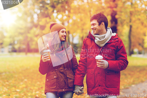 Image of happy couple with coffee walking in autumn park
