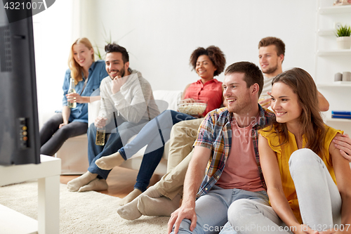 Image of happy friends with popcorn watching tv at home