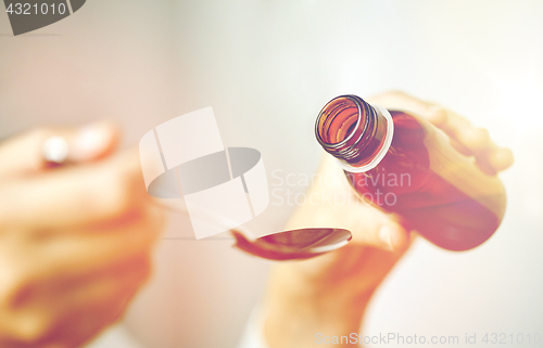 Image of woman pouring medication from bottle to spoon