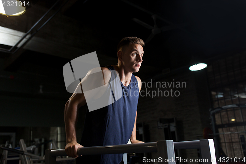 Image of man doing triceps dip on parallel bars in gym