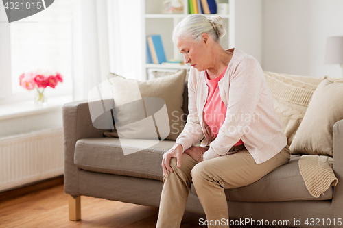 Image of senior woman suffering from pain in leg at home