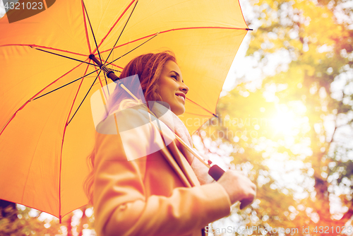 Image of happy woman with umbrella walking in autumn park