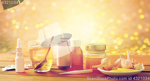 Image of drugs, thermometer, honey and cup of tea on wood