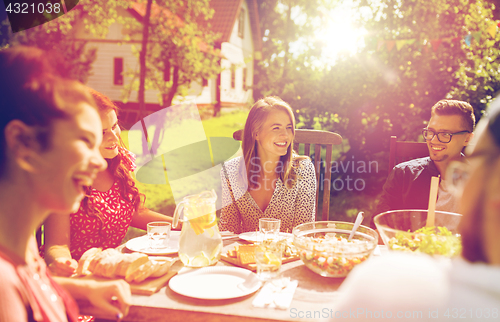 Image of happy friends having dinner at summer garden party