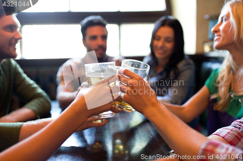 Image of happy friends drinking beer at bar or pub