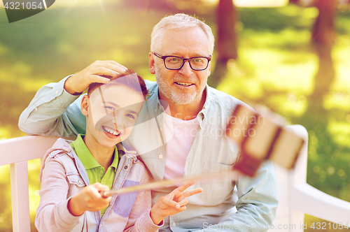 Image of old man and boy taking selfie by smartphone