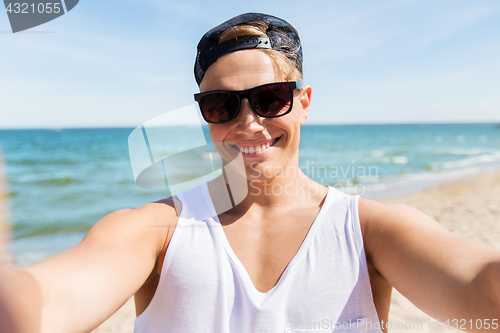 Image of man in sunglasses taking selfie on summer beach