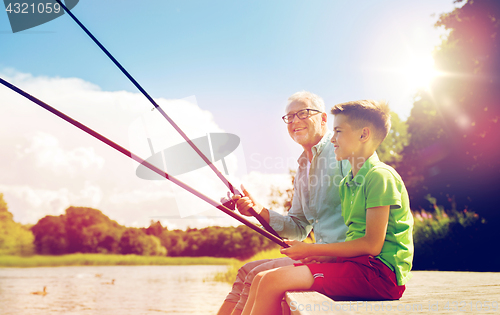 Image of grandfather and grandson fishing on river berth