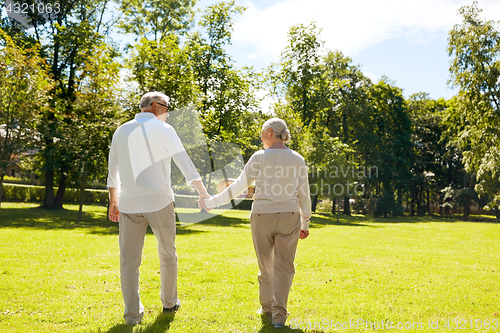 Image of happy senior couple walking at summer city park