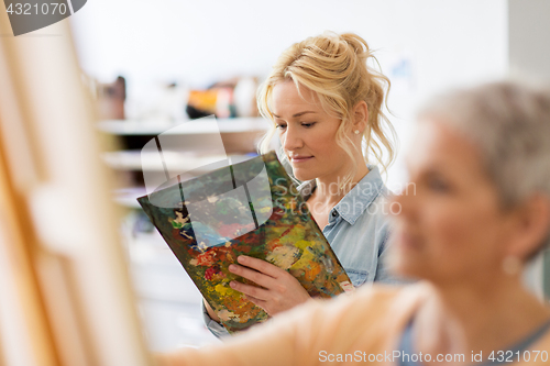 Image of woman artist with palette painting at art school