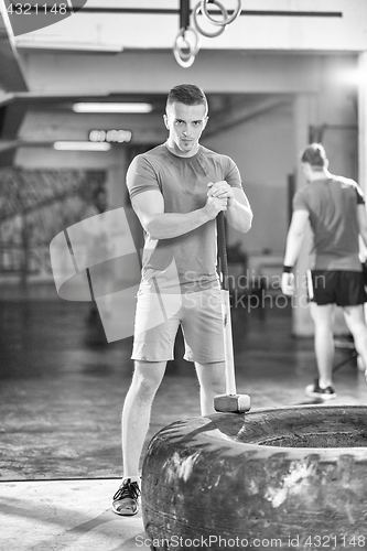 Image of man workout with hammer and tractor tire