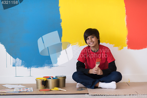 Image of young boy painter resting after painting the wall