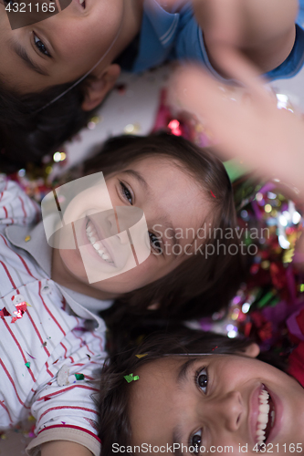 Image of kids  blowing confetti while lying on the floor