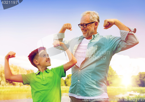 Image of happy grandfather and grandson showing muscles