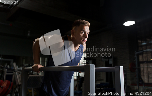 Image of man doing triceps dip on parallel bars in gym