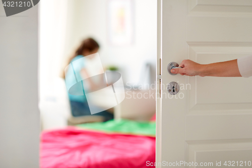 Image of mother hand opening door to girl room