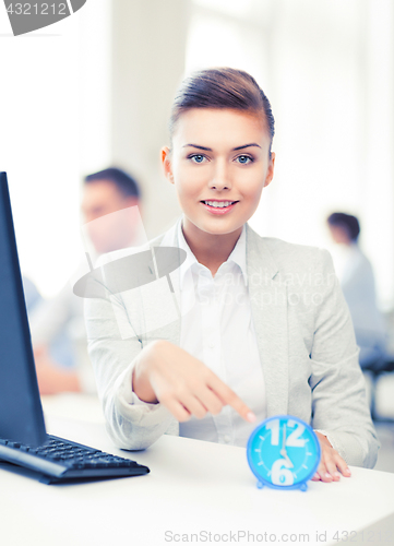 Image of businesswoman pointing at clock in office