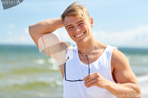 Image of smiling young man with sunglasses on summer beach