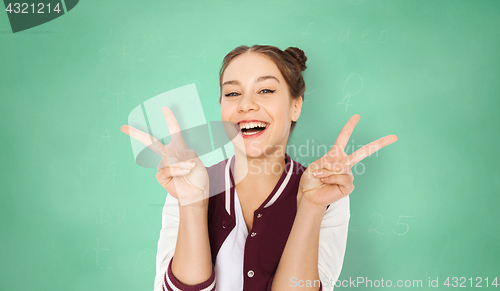 Image of happy student girl showing peace sign over green