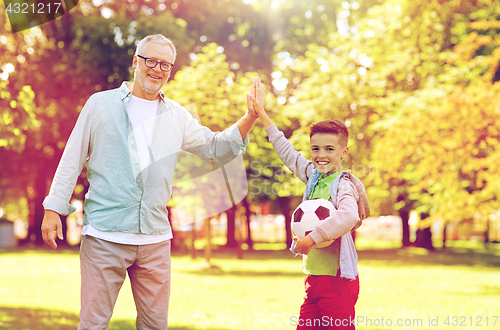 Image of old man and boy with soccer ball making high five