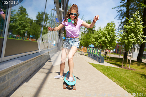 Image of happy teenage girl in shades riding on longboard