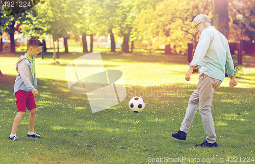 Image of old man and boy playing football at summer park