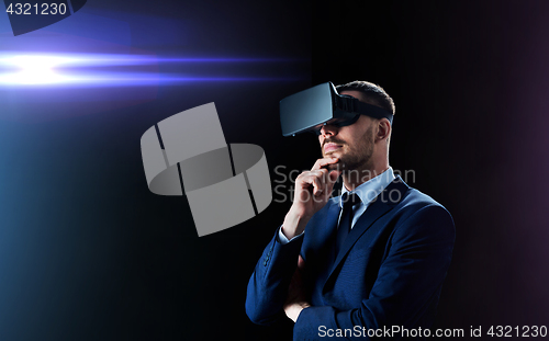 Image of businessman in virtual reality headset over black