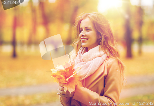 Image of beautiful woman with maple leaves in autumn park