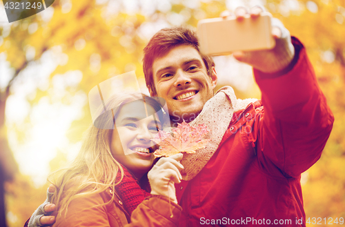 Image of couple taking selfie by smartphone in autumn park