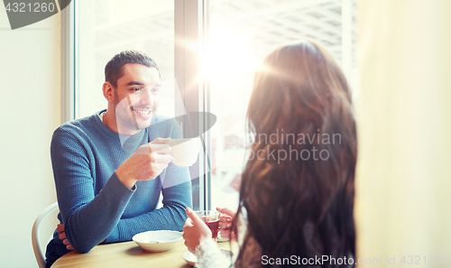 Image of happy couple drinking tea and coffee at cafe