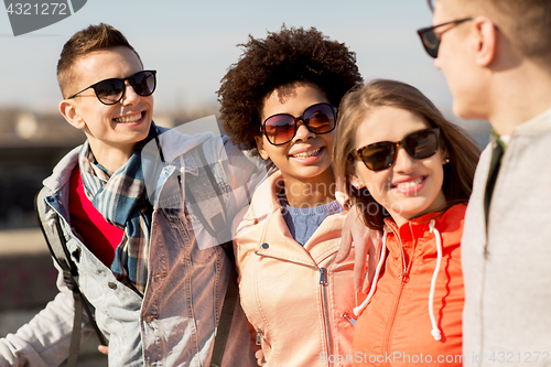 Image of happy teenage friends in shades talking on street