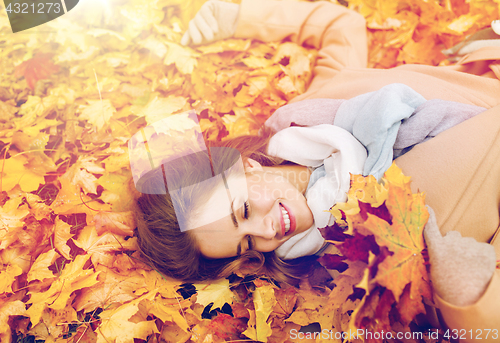 Image of beautiful happy woman lying on autumn leaves