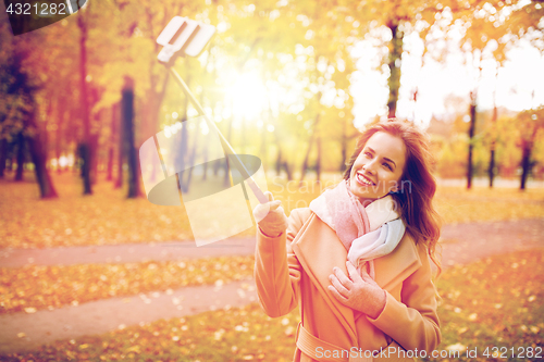 Image of woman taking selfie by smartphone in autumn park