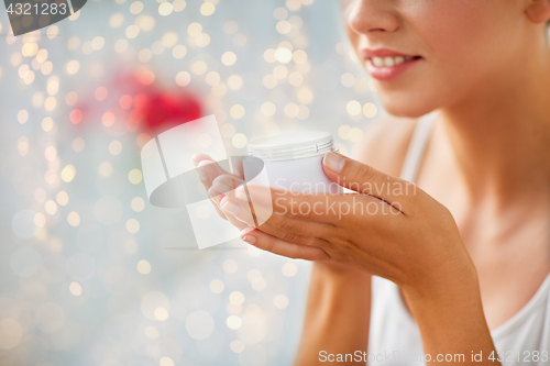 Image of close up of happy woman holding and smelling cream