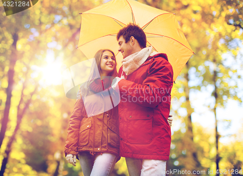 Image of smiling couple with umbrella in autumn park