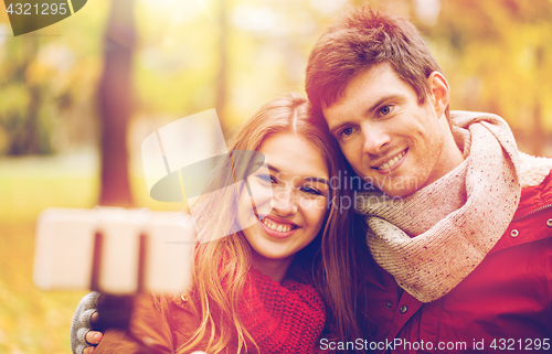 Image of couple taking selfie by smartphone in autumn park
