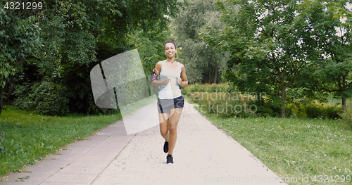 Image of Cheerful woman running in park