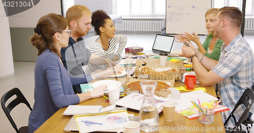Image of Colleagues eating pizza at office table