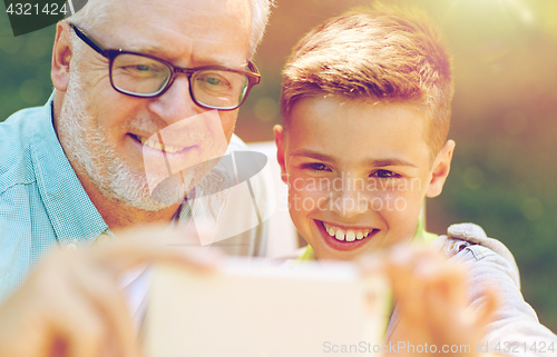Image of old man and boy taking selfie by smartphone