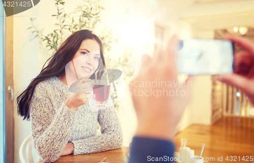 Image of man taking picture of woman by smartphone at cafe