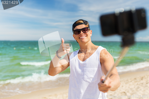 Image of man with smartphone taking selfie on summer beach