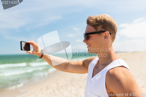 Image of man with smartphone photographing on summer beach