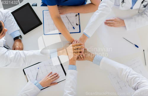 Image of group of doctors holding hands together at table